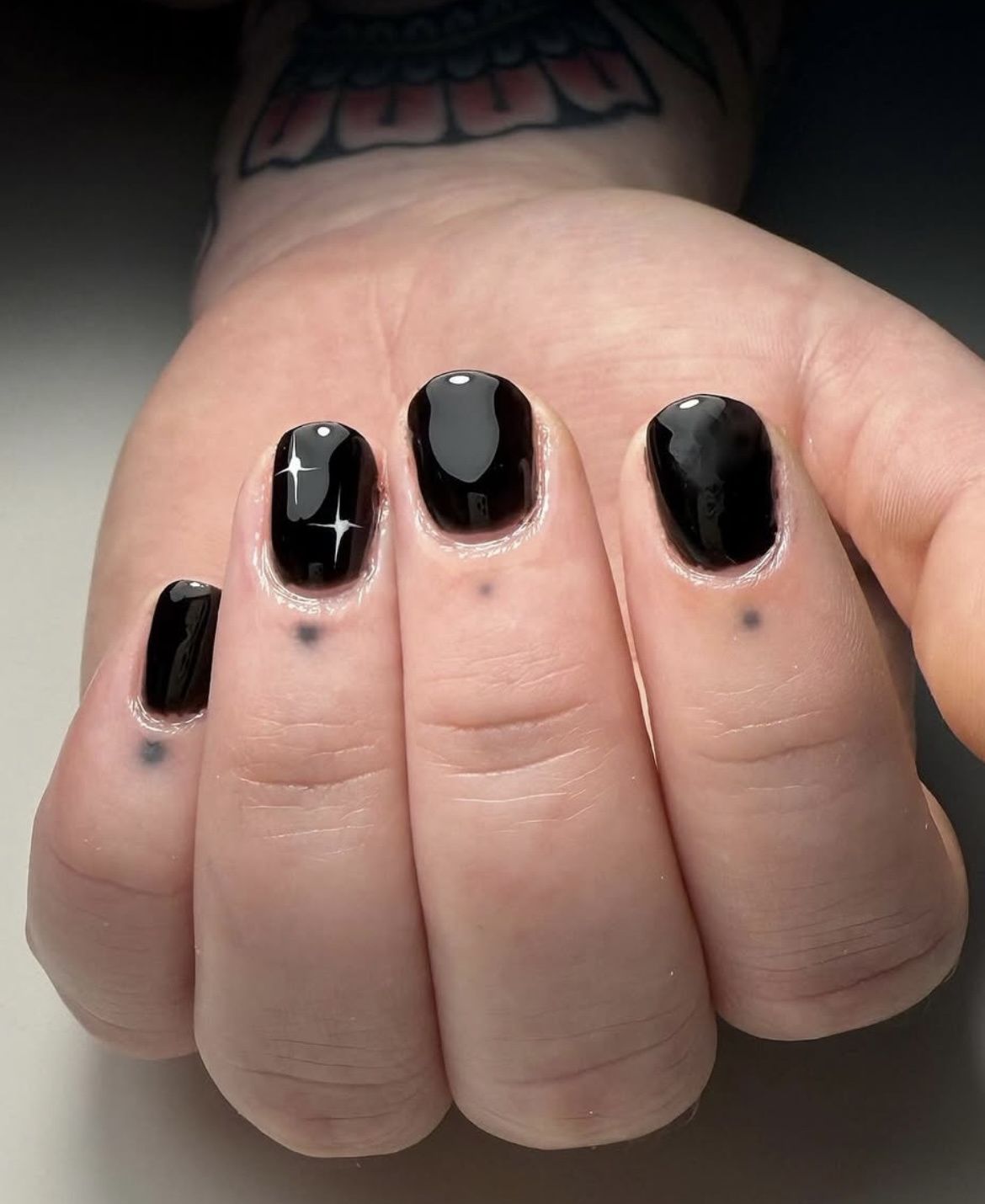 Short glossy black nails with a painted sparkle