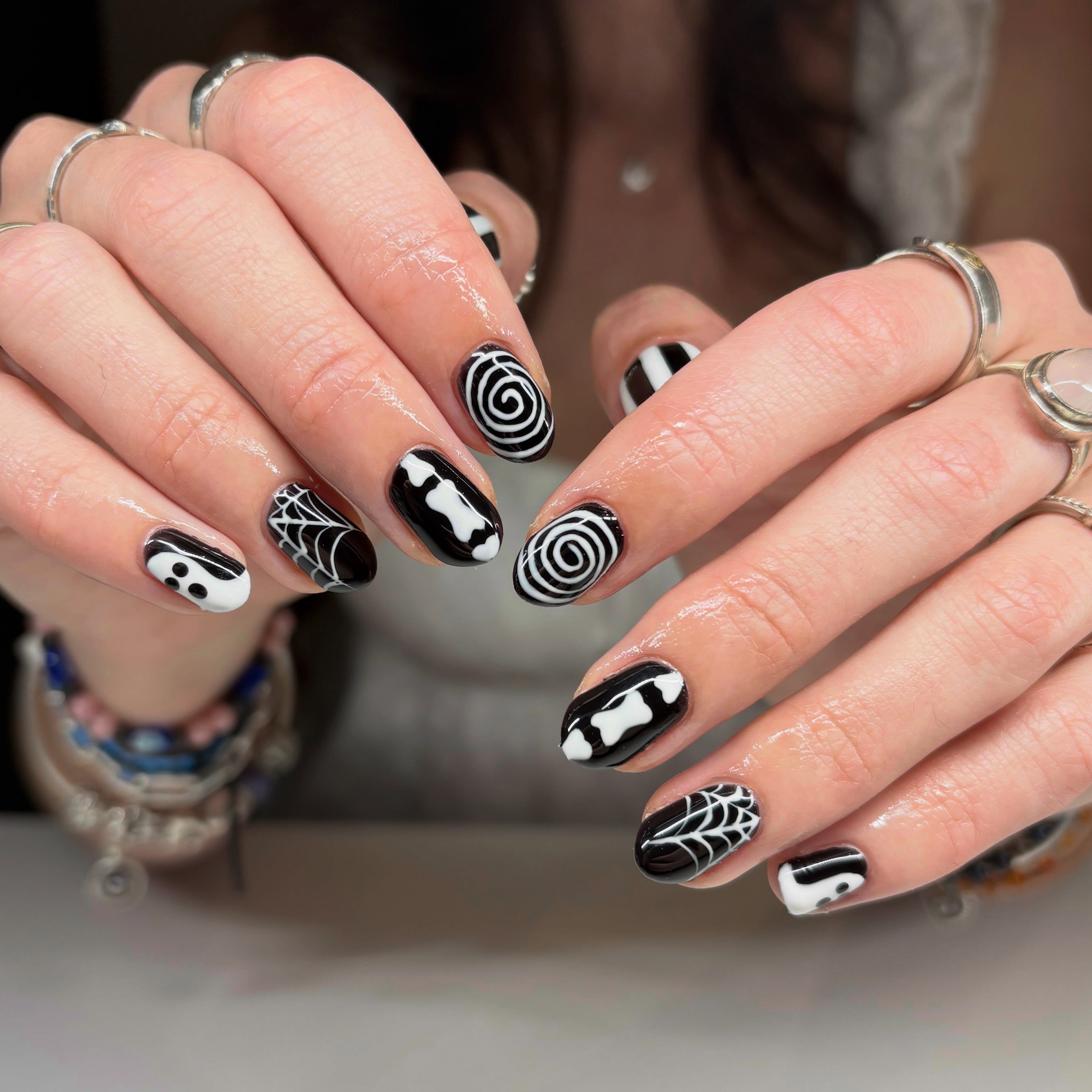 Black and white nails with swirls, spider webs, bones and ghosts